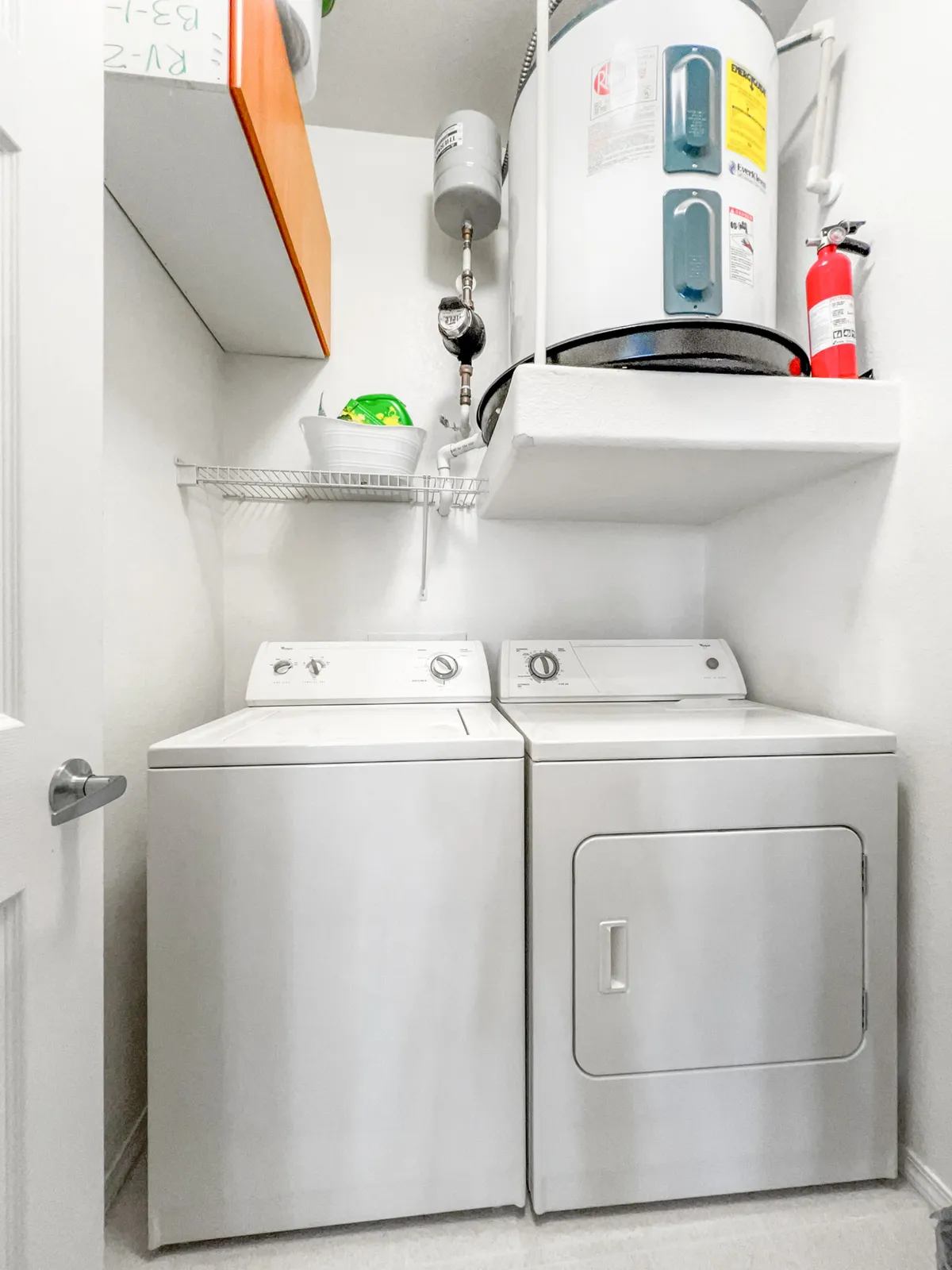 A full-sized laundry room equipped with a washing machine, dryer, water heater, and shelves for organization. The space feels efficient and tidy, ideal for managing extended stays or daily routines.