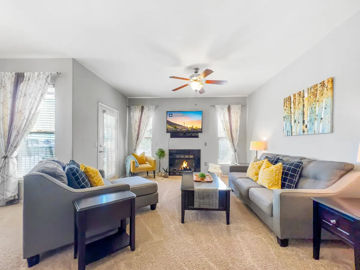 A welcoming living room with a fireplace, cozy sofas (including a convertible option), a television, decorative artwork, and a coffee table. The design invites family gatherings, movie nights, and relaxation, providing flexible accommodation options for guests.