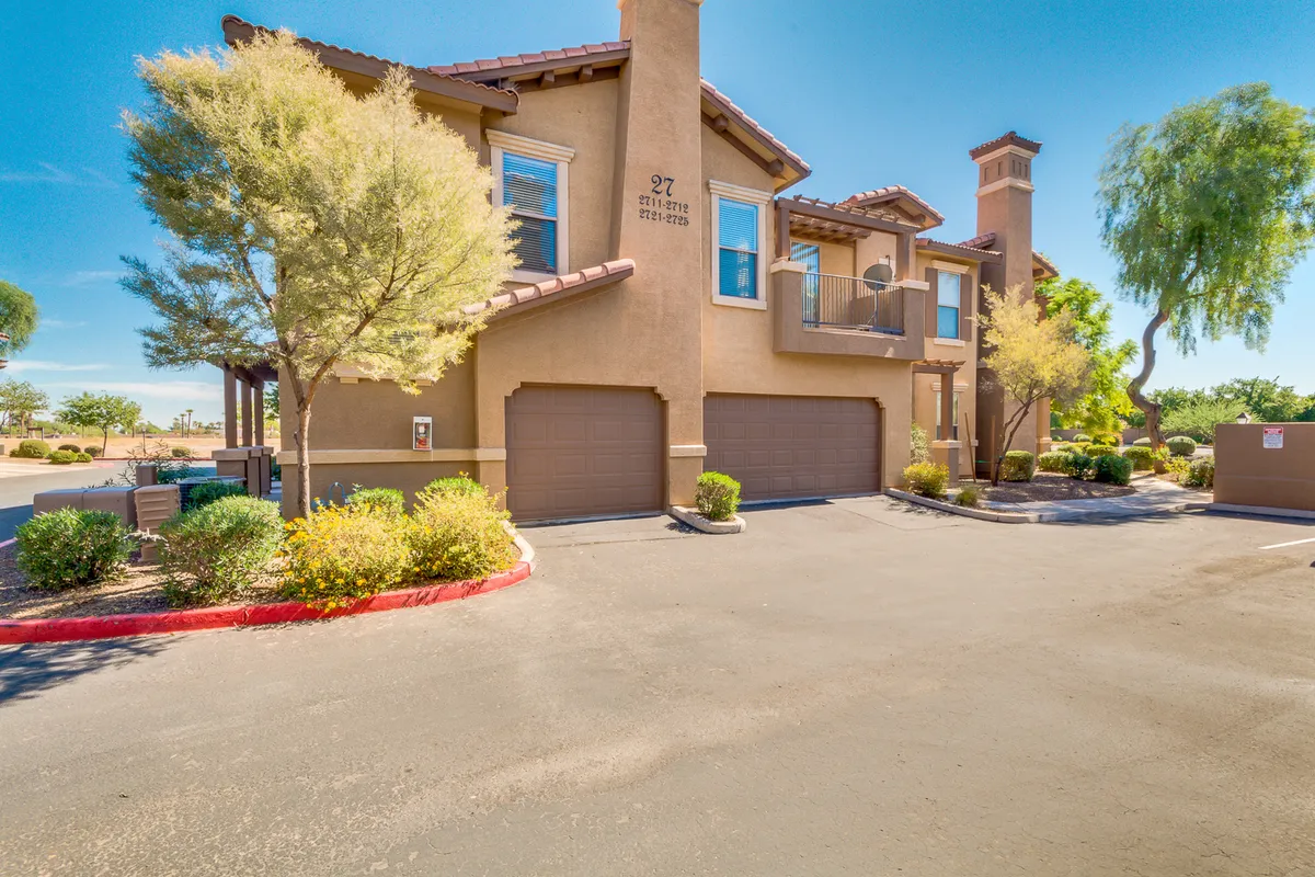 The image showcases the building’s attractive facade, bordered by lush, well-kept gardens and a visible parking area. There’s a sense of an active, friendly community where residents can enjoy outdoor gatherings, barbecues, and leisure walks—especially with balconies and patios visible.