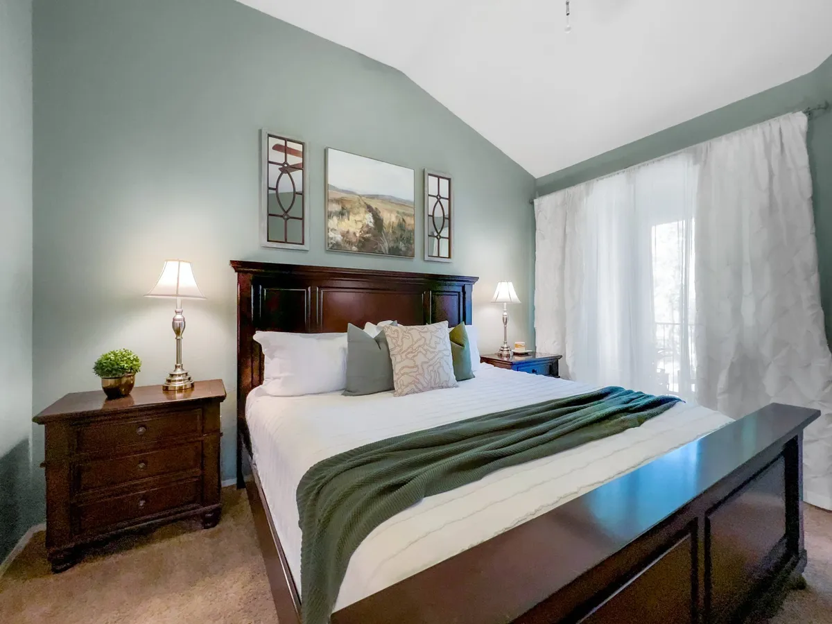 A second bedroom with a neatly made bed, decorative pillows, nightstands with lamps, and calming wall art. The room is filled with gentle natural light, creating a serene and inviting atmosphere ideal for peaceful sleep.