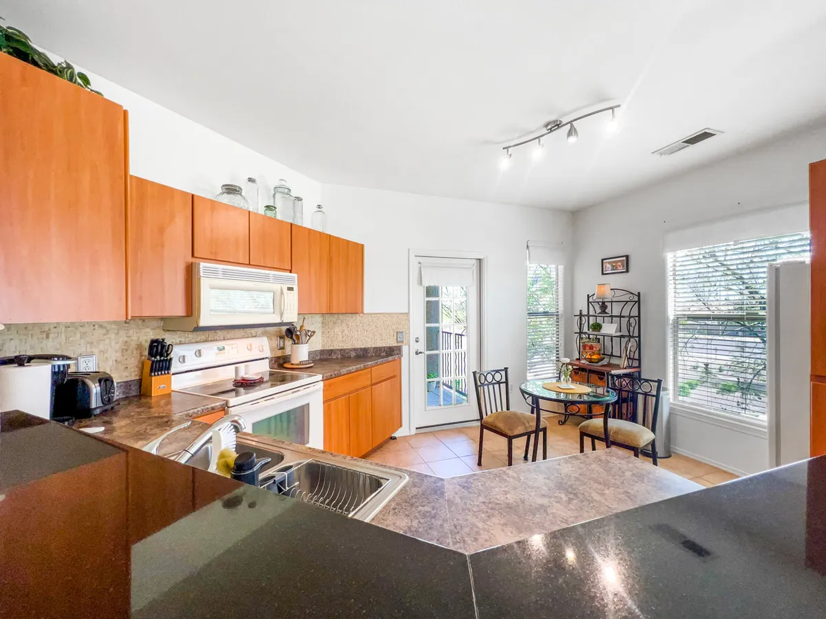 A bright kitchen featuring a central island, dining table, and generous windows that fill the space with natural light. The island and table are perfectly positioned for casual dining, entertaining, or starting the day at the breakfast bar.