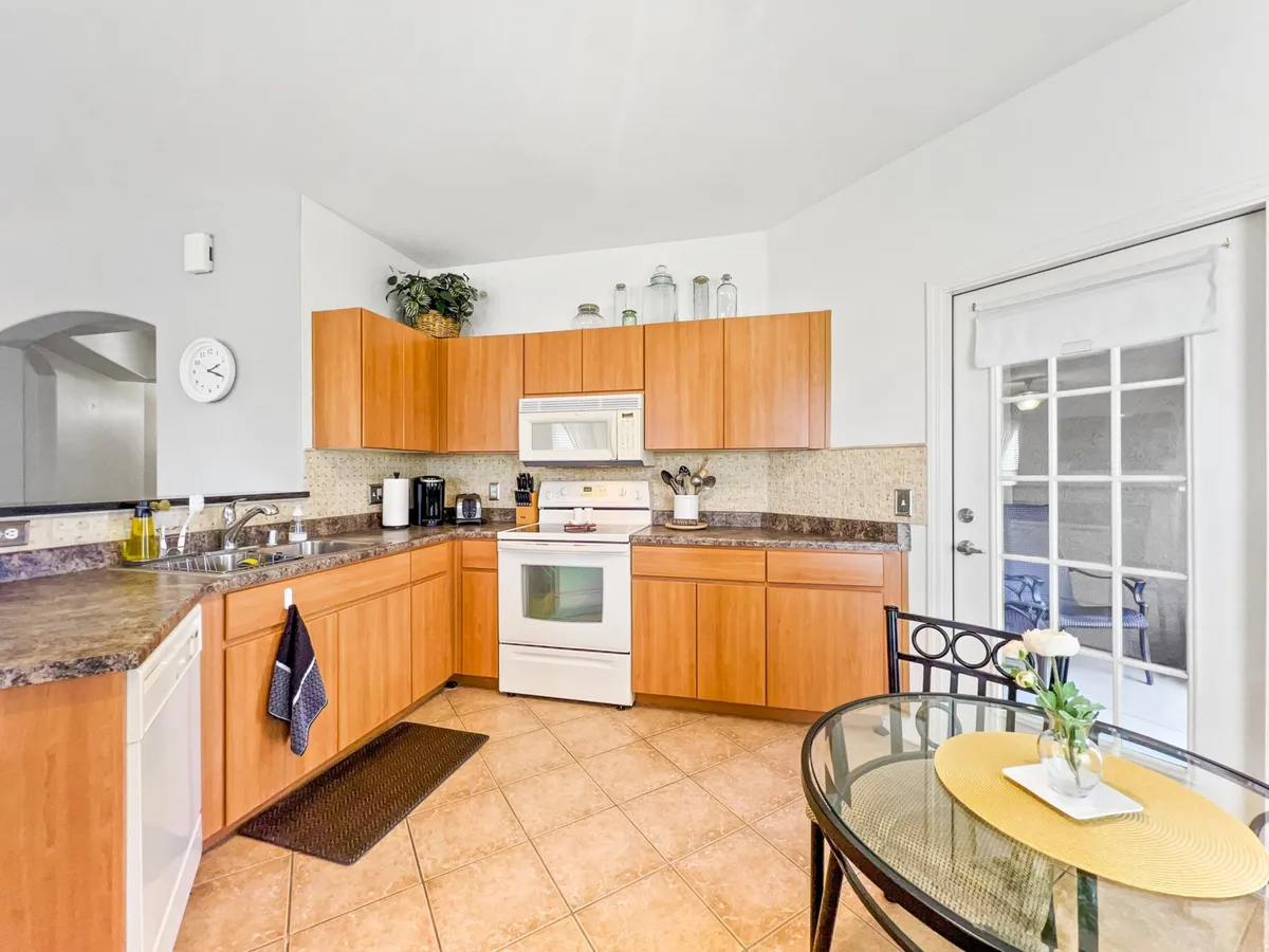 An open-concept kitchen with sleek cabinetry and stainless steel appliances flows into a spacious dining area with a large table and a decorative plant centerpiece. The scene radiates warmth, ideal for family meals and celebrations.